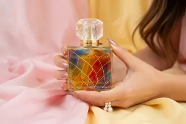 Hands holding a Miamora bottle against soft pink fabric